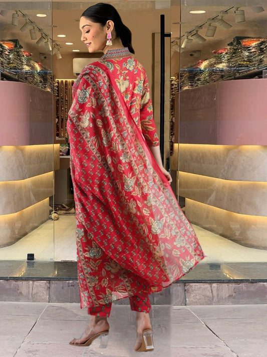 Woman in a red floral outfit standing in a modern interior setting